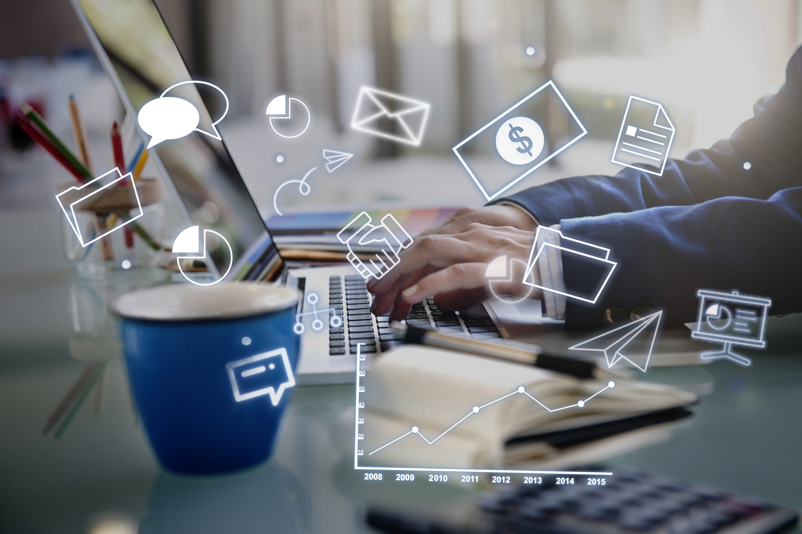 This image shows a person working on a laptop, likely in a professional or business environment. The person is typing on the keyboard, and around the laptop are digitally added floating icons representing different business and digital concepts.Some of the visible icons include: A chat bubble (communication) A pie chart and line graph (data analysis/analytics) A paper airplane (sending/sharing information) A handshake (business deals/partnership) A document icon (files or reports) A dollar bill symbol (finance/money) A presentation board (business presentation) On the desk, there is also a blue coffee cup, a notebook, some pencils in a holder, and a calculator. The overall theme of the image seems to represent digital business, online work, finance, communication, and data management in a modern professional setting.